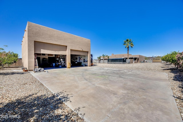 exterior space featuring an outdoor structure, fence, a garage, and stucco siding