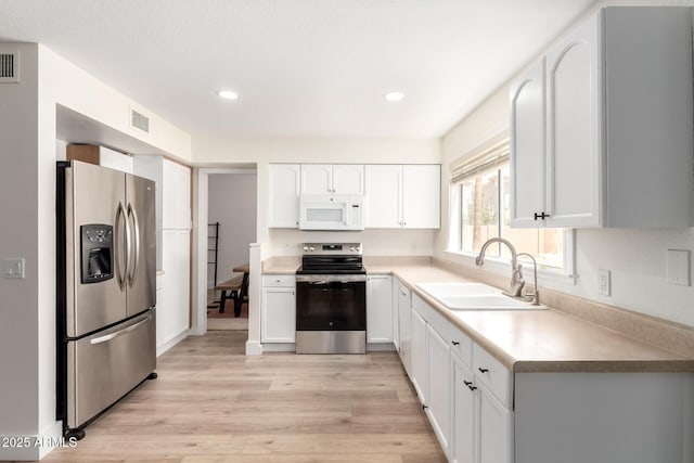 7702 W Piute Ave, Glendale, AZ 85308 - kitchen with appliances with stainless steel finishes, a sink, light wood-type flooring, white cabinetry, and recessed lighting