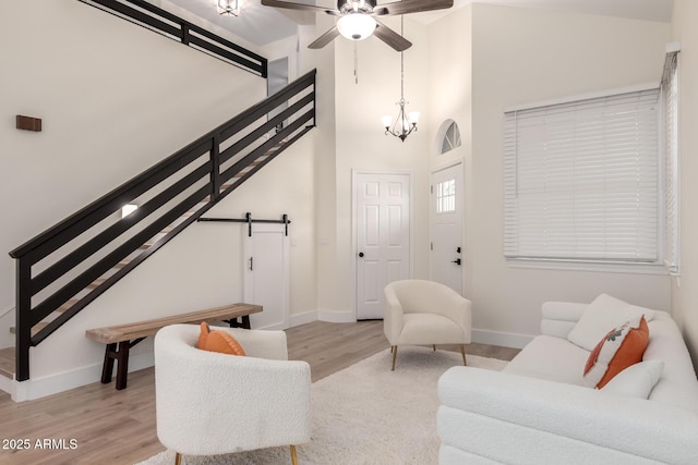 7702 W Piute Ave, Glendale, AZ 85308 - living room featuring light wood-type flooring, baseboards, a barn door, a ceiling fan, and a towering ceiling
