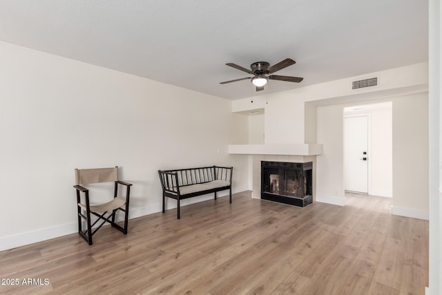 7702 W Piute Ave, Glendale, AZ 85308 - living area with a ceiling fan, light wood-style flooring, a tile fireplace, and baseboards