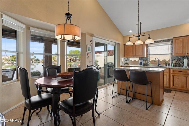 dining space with light tile patterned floors, high vaulted ceiling, and baseboards