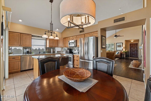 dining area with high vaulted ceiling, a ceiling fan, visible vents, and light tile patterned flooring