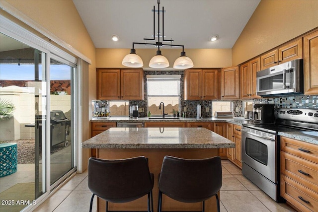 kitchen featuring appliances with stainless steel finishes, a kitchen island, a sink, and brown cabinets