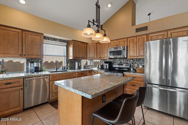 kitchen featuring a sink, visible vents, appliances with stainless steel finishes, backsplash, and brown cabinets