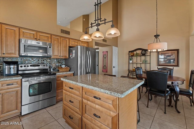 kitchen featuring a center island, light tile patterned floors, tasteful backsplash, visible vents, and appliances with stainless steel finishes