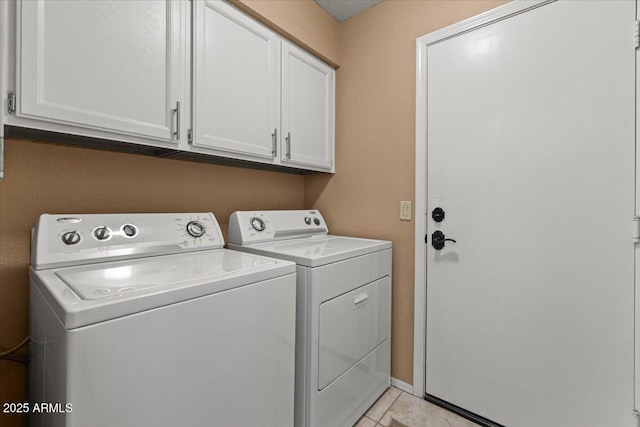 laundry area with light tile patterned flooring, washing machine and dryer, and cabinet space