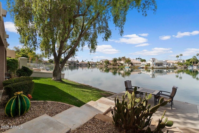 exterior space featuring a water view, fence, and a lawn