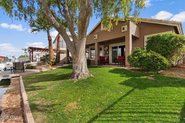 rear view of property with a patio area, stucco siding, a yard, and a pergola