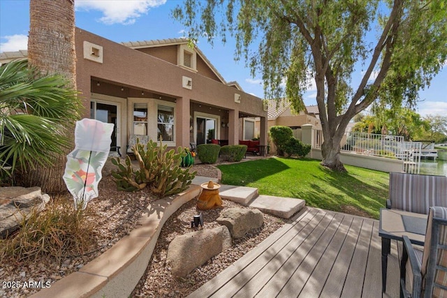 rear view of property featuring a yard and stucco siding