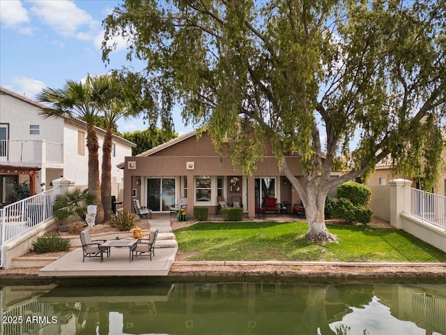 rear view of property with a water view, a fenced backyard, a lawn, and a patio