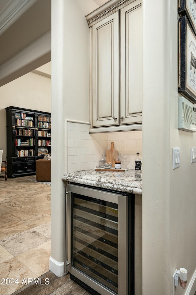 bar featuring light stone countertops, decorative backsplash, light wood-type flooring, and beverage cooler