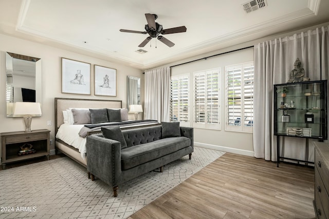 bedroom featuring ceiling fan, a raised ceiling, and light hardwood / wood-style flooring