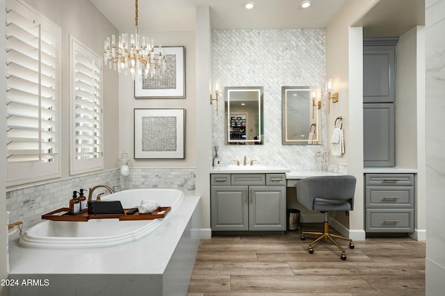 bathroom featuring a notable chandelier, vanity, wood-type flooring, and a washtub