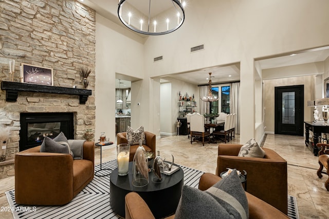 living room featuring a stone fireplace, a high ceiling, and an inviting chandelier