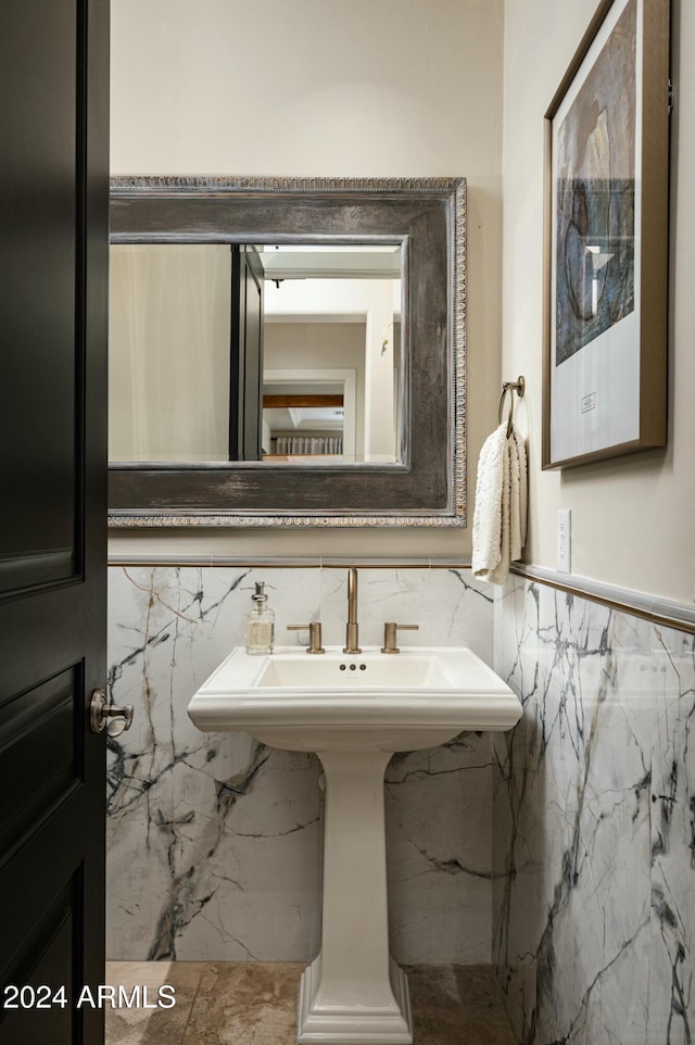 bathroom featuring sink and tile walls