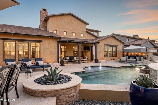 back house at dusk with a patio, an outdoor hangout area, and pool water feature