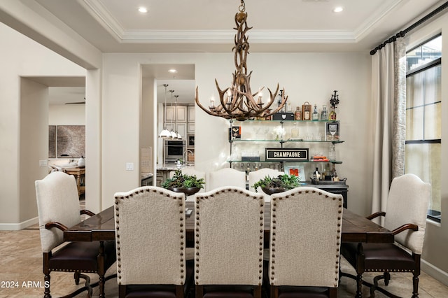 dining area with a tray ceiling, crown molding, tile patterned flooring, and a notable chandelier