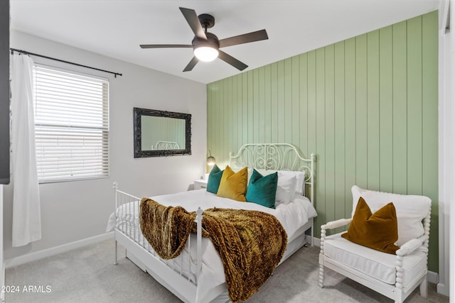 bedroom with light carpet, ceiling fan, and wood walls