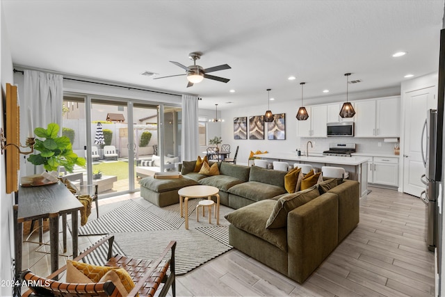 living room featuring ceiling fan, sink, and light wood-type flooring