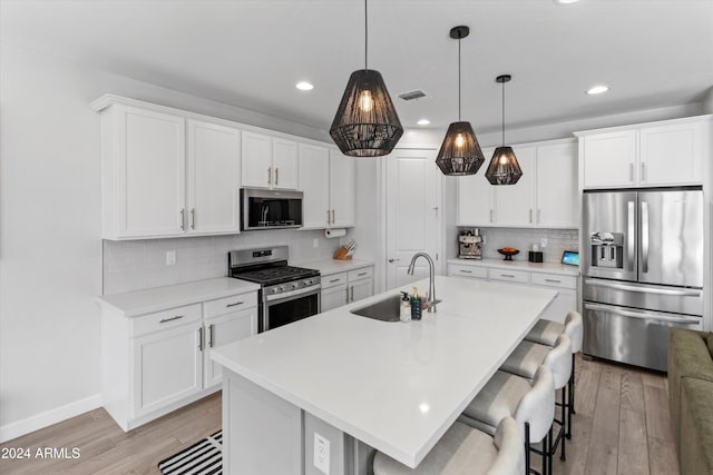 kitchen with stainless steel appliances, an island with sink, sink, and white cabinets