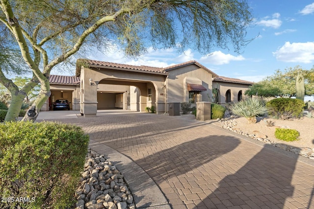 mediterranean / spanish-style home featuring decorative driveway, stucco siding, and a tiled roof