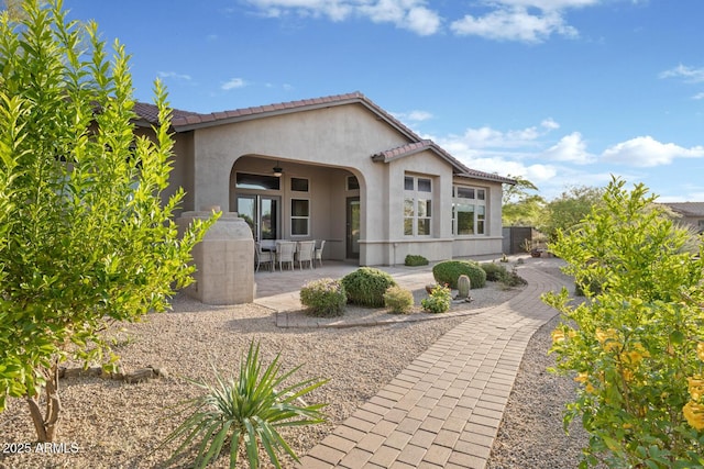 rear view of house with stucco siding, a patio area, and a tile roof