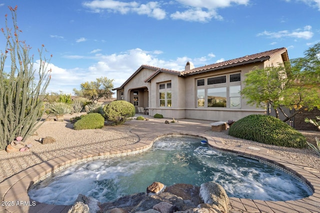 back of house with a chimney, a tile roof, an outdoor pool, a patio area, and stucco siding