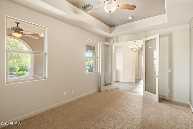 carpeted empty room with french doors, visible vents, ceiling fan with notable chandelier, and a wealth of natural light