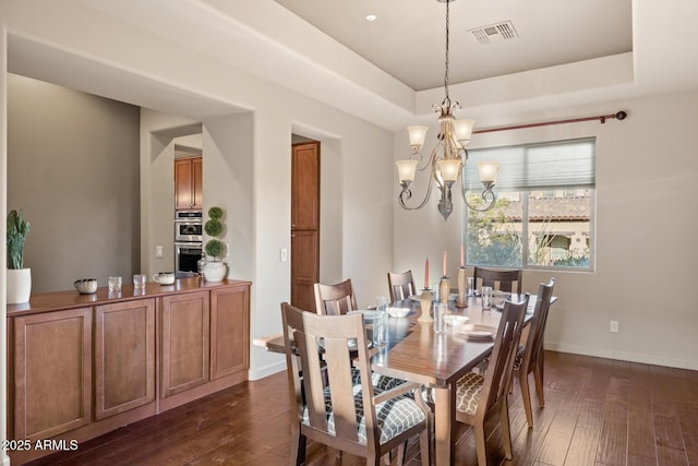 dining area featuring dark wood-style flooring, a tray ceiling, visible vents, and an inviting chandelier
