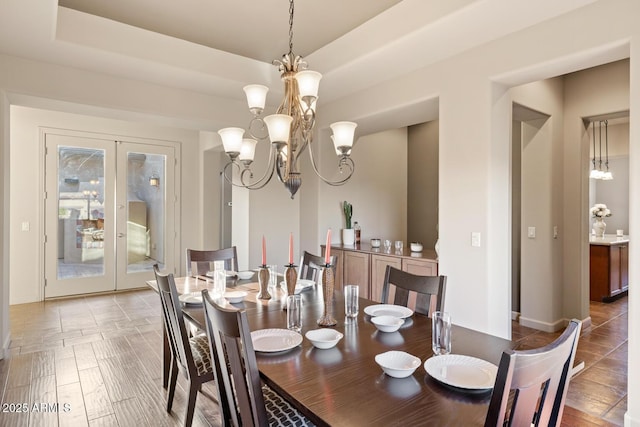 dining space with baseboards, a notable chandelier, and french doors
