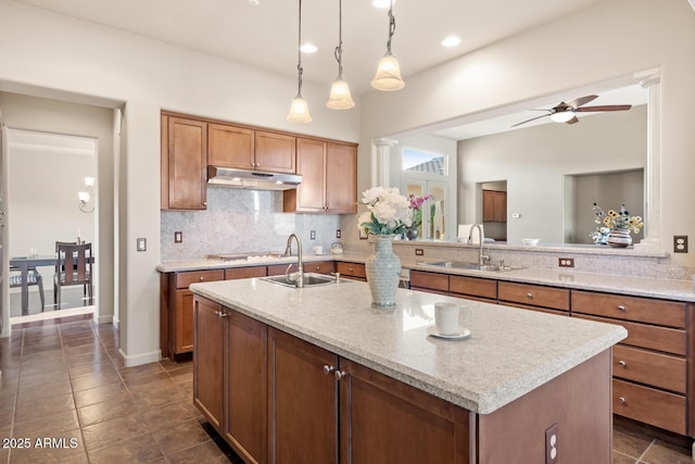 kitchen with under cabinet range hood, ceiling fan, a sink, and tasteful backsplash