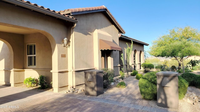 view of side of home featuring stucco siding and a tiled roof