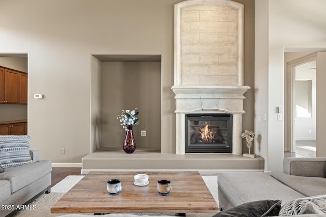 living room with baseboards, a glass covered fireplace, and wood finished floors