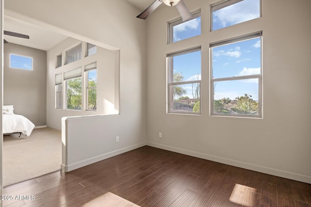 unfurnished bedroom featuring baseboards, dark wood-type flooring, and ceiling fan