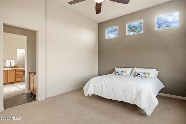 bedroom with light colored carpet, a sink, baseboards, and ensuite bath