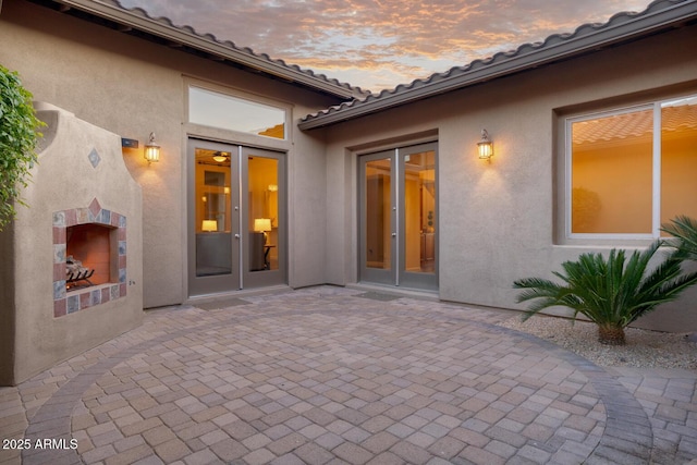 back of property at dusk featuring a patio and stucco siding
