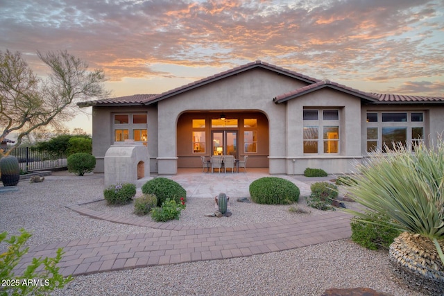 rear view of house with fence, stucco siding, a patio area, and a tile roof