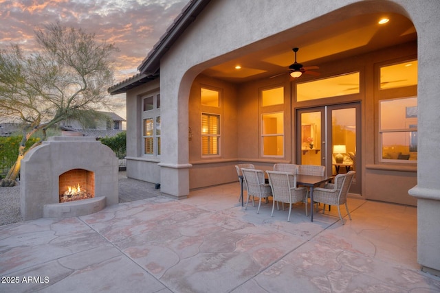 view of patio / terrace with outdoor dining area and a warm lit fireplace