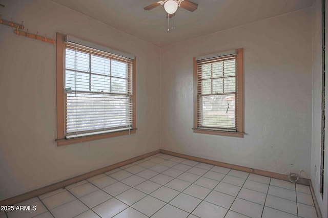 spare room featuring light tile patterned flooring, a wealth of natural light, and a ceiling fan