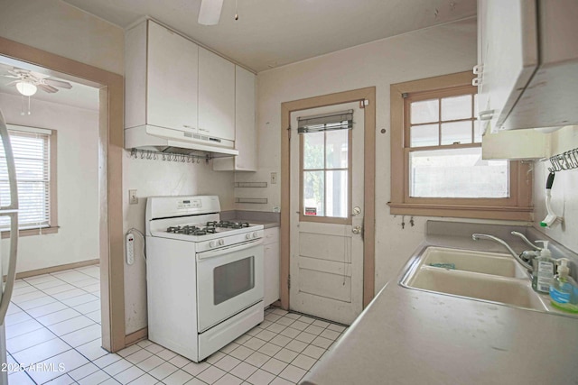 kitchen featuring white cabinets, white gas range, light countertops, under cabinet range hood, and a sink