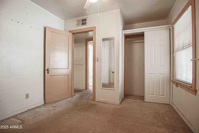 unfurnished bedroom featuring a ceiling fan, visible vents, a closet, and light colored carpet