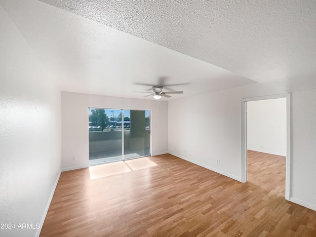 unfurnished room with ceiling fan, a textured ceiling, and light wood-type flooring