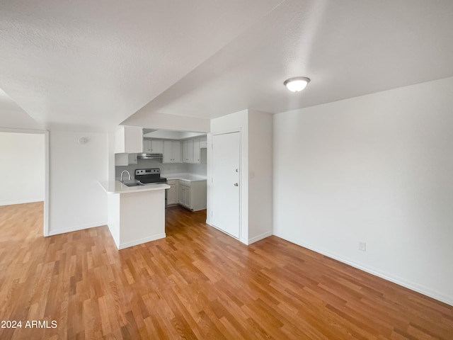 kitchen featuring sink, a textured ceiling, electric range, kitchen peninsula, and light hardwood / wood-style floors