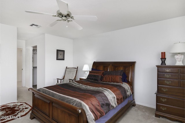 bedroom with ceiling fan, a walk in closet, a closet, and light carpet