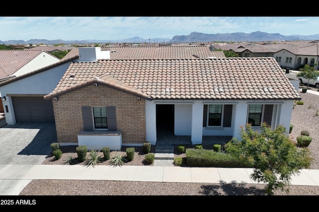 view of front of property with a mountain view, an attached garage, driveway, and a tile roof