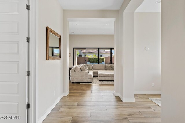 hall featuring baseboards and light wood-style flooring