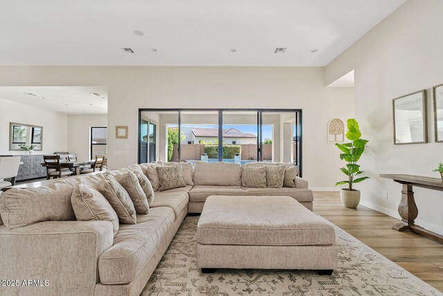 living room featuring light wood-type flooring, recessed lighting, baseboards, and visible vents