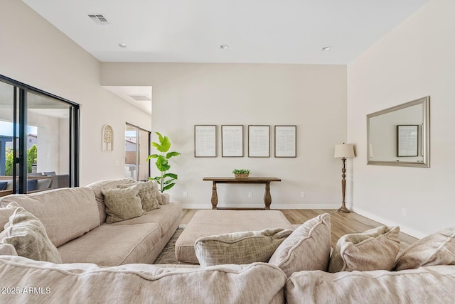 living area featuring baseboards, light wood-type flooring, and visible vents