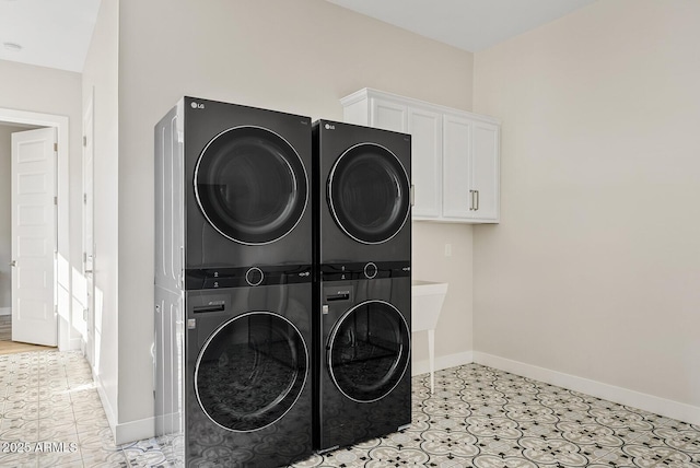laundry room with baseboards, cabinet space, and stacked washer / dryer