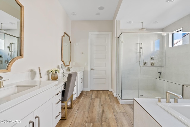 full bath featuring a stall shower, wood finished floors, and two vanities